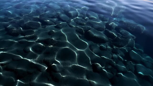 Oblique aerial view of shallow underwater rock field with sunlight caustics revealing textured