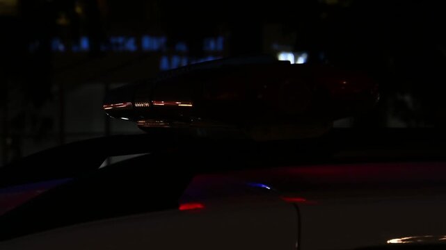 Police patrol car with flashing red and blue lights on roof at night, close up, motion footage.
