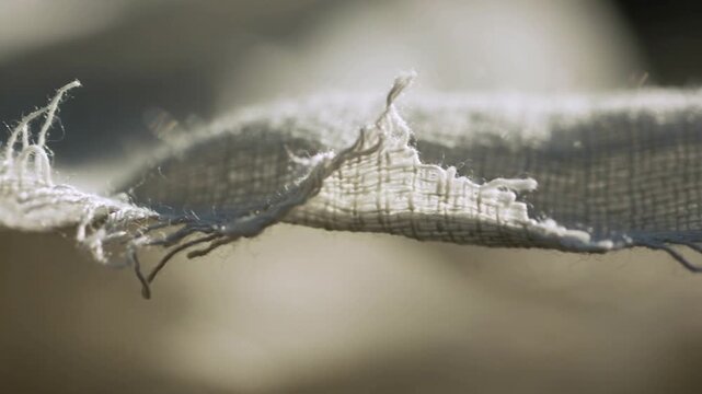 Refocusing camera revealing weave and frayed edge shifting at home by window, threads swinging