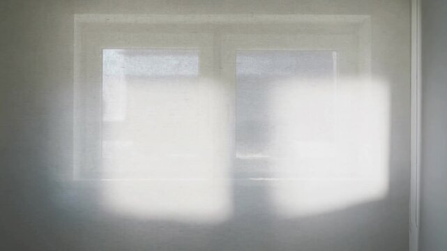 Shifting sunlight slipping across double-pane window in room as sun shifts casting bright patches