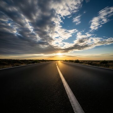 Empty asphalt road stretching into the horizon at sunset with dramatic sky
