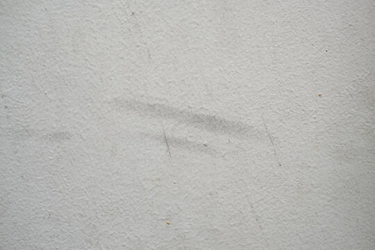 White concrete wall texture background with subtle scuffs and scratches. Minimalist abstract background of a white plastered wall with grunge details.