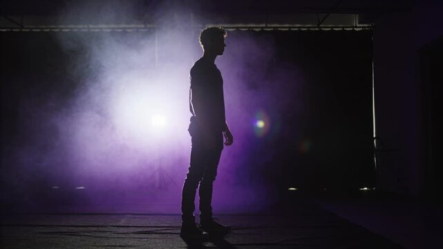 Entering man slowing and standing in studio, creating purple silhouette, fog, backlight, fitted top