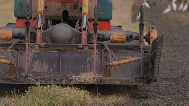 Agriculture tractor plow field soil machinery farm equipment rural cultivation with old cultivator implement working muddy farmland grass stubble blade wheel spring metal tool