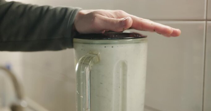 Caucasian man makes sauce mixing in blender. Single male is cooking at kitchen at home. 4K 10-bit