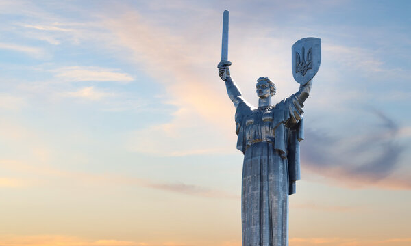 The Motherland Monument in Kyiv stands tall against a dramatic sunset sky, representing strength, resilience, history, national pride, and Ukrainian heritage. Ukraine national sculpture.