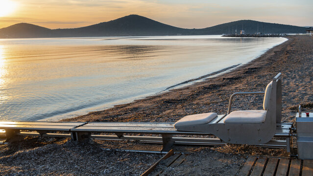 Accessible beach with sea access system for people with disabilities at sunrise in Greece. Inclusive tourism and barrier-free recreation, wheelchair friendly public facility on Greek coast