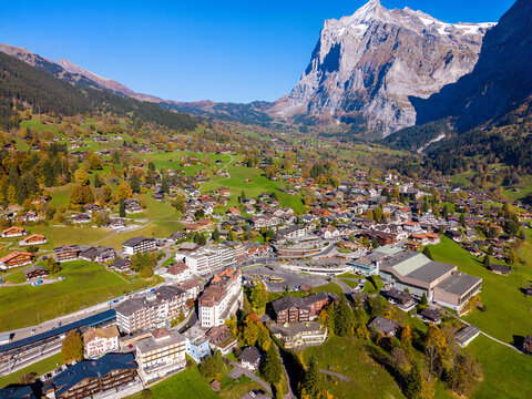 Aerial autumn view of Grindelwald alpine village with traditional chalets on green hills. Grindelwald, Canton of Bern, Switzerland.