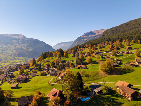 Aerial autumn view of Grindelwald alpine village with traditional chalets on green hills. Grindelwald, Canton of Bern, Switzerland.