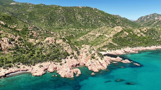 4K drone flight along the Marina di Gairo coastline, featuring Su Sirboni Beach and Cala Laus. Turquoise waters, striking red rocks, and the unspoiled beauty of Sardinia, Italy