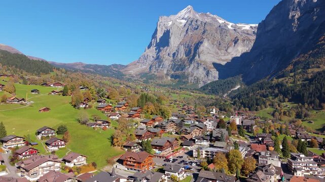 Aerial autumn view of Grindelwald alpine village with traditional chalets on green hills. Grindelwald, Canton of Bern, Switzerland.