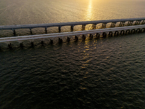Aerial view of the long pier at Puerto Progreso stretching into the sea during golden hour with calm water and warm sunlight reflecting on the surface in Progreso, Yucatan, Mexico.