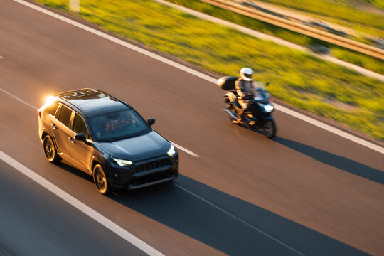 SUV and Touring Motorcycle Driving on Highway at Golden Hour