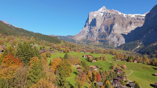 Aerial autumn view of Grindelwald alpine village with traditional chalets on green hills. Grindelwald, Canton of Bern, Switzerland.
