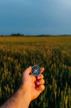 Compass in hand against a background of a wheat field