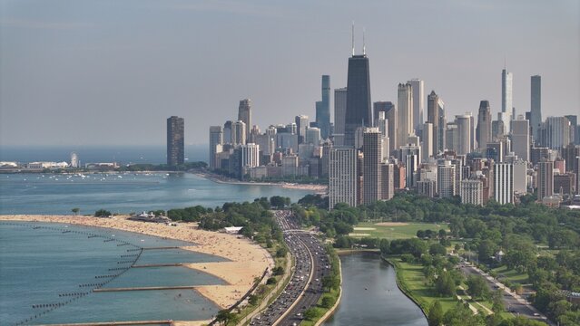 Aerial view of the Chicago skyline featuring the John Hancock Center, Lake Michigan shoreline, sandy beaches, and the busy Lake Shore Drive in Chicago, Illinois, United States.