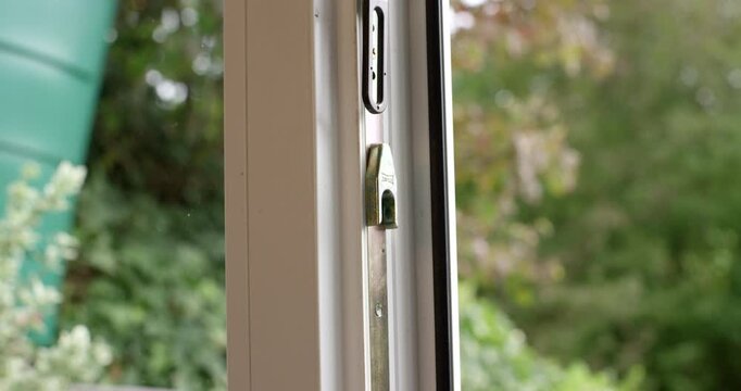 Close-up shot of a window locking mechanism showing a metal pin inside a white PVC frame