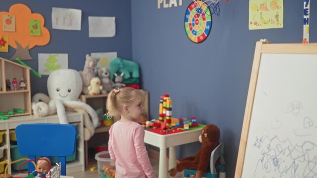 Little blonde girl hugging a large stuffed monkey with hands in a studio playroom; playful innocence.