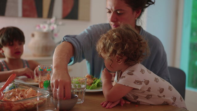 Toddler reaching across table grabbing food with hand during family meal curious childhood moment of self feeding exploration and interaction during shared dining time