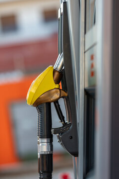 Yellow Gasoline Fuel Pump Nozzle in Holster on Silver Petrol Dispenser Close Up