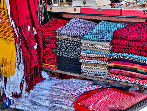 Stacks of colorful traditional ethnic woven fabrics and handmade textiles on display at a local market. Great for asian culture, travel souvenir, and fashion textile concepts.