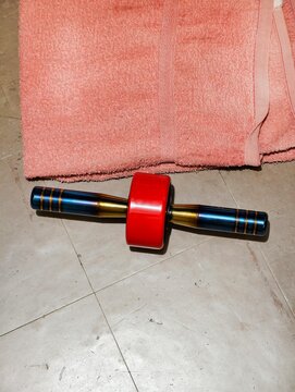A top view of a modern abdominal wheel exercise roller with custom titanium rainbow handles and red wheel. Perfect for home workout, fitness equipment, and healthy lifestyle concepts.