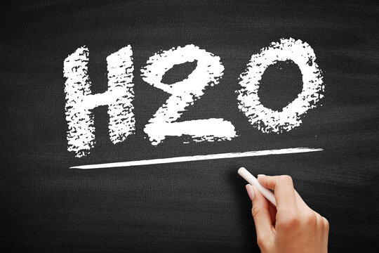 H2O chemical formula for water written in chalk. Hand underlining the molecular symbol representing liquid hydration and essential life in a school classroom setting.