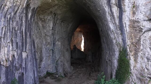 The camera slowly pulls back, revealing the cave's massive scale and its magnificent, naturally textured vertical rock walls.