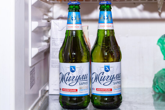 Two bottles of non alcoholic zhiguli beer standing inside a white refrigerator shelf