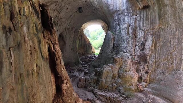 The camera slowly pans, revealing majestic rock wall structures, natural rock textures formed over millennia, and the stalactites and stalagmites adorning the cave ceiling.