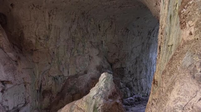 revealing majestic cave wall formations with natural textures, before finally unveiling a spectacular view outside the cave&mdash;surrounded by steep cliffs and lush green trees beneath a clear blue sky.