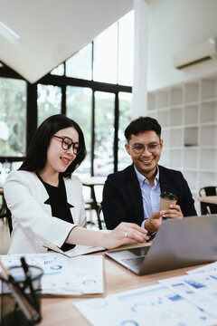 Two business professionals collaborating on a laptop in a modern office, discussing ideas and reviewing projects, showcasing teamwork, productivity, and workplace communication.