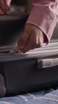 Vertical shot of woman stuffing clothes inside overpacked suitcase and zipping it closed. Clip is perfect for travel marketing campaigns and luggage brand promotions