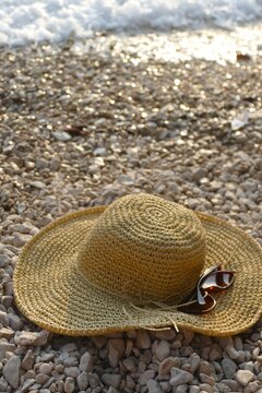 Women's woven summer hat and glass on the beach summer fashion accessory background