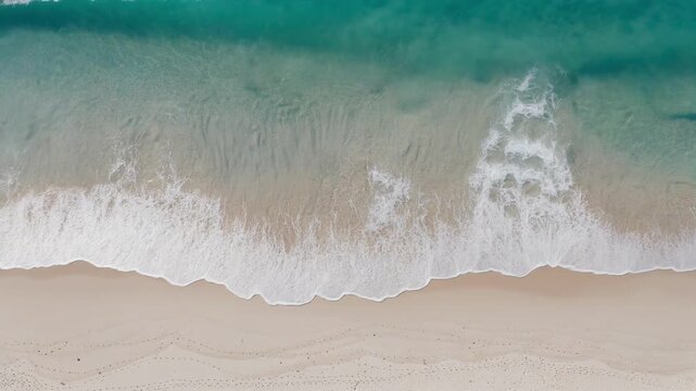 Gentle ocean waves roll onto pristine sandy beach, creating serene atmosphere under clear turquoise water, perfect for relaxation