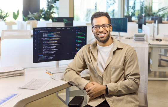 Programmer developer coding software engineer man portrait. Confident professional at computer monitor in open office shows code and conveys teamwork. Modern coding and teamwork concept.