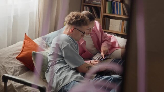High angle view of Caucasian young adult couple sitting on bed, holding passports and using laptop to plan travel itinerary. Clip is ideal for online booking platforms and vacation planning services