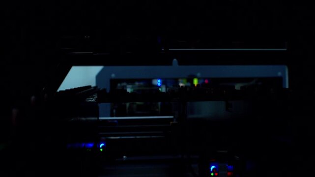 Automated surface mount technology machine assembling a circuit board. Premium low-key footage of advanced industrial factory line.