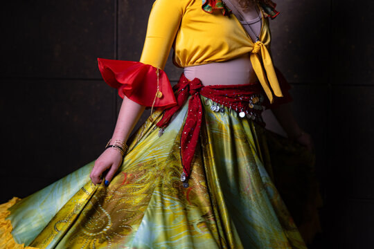 Gypsy dancer holding colourful costume with coin scarf close up on dark background