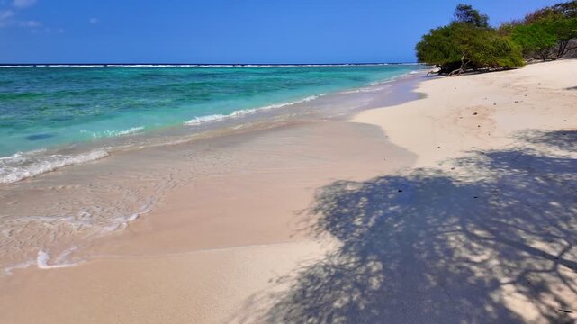 static shot of ocean with calm waves reaching shore of sand beach on tropical Gili island Indonesia during sunny day, holidays, vacations, relax, paradise and tourism concept