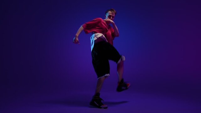 HipHop dancer performing energetic freestyle move in purple studio