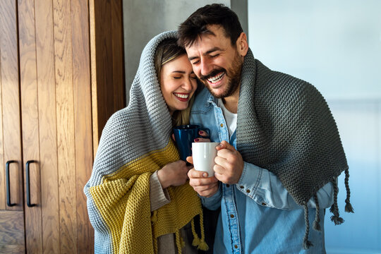 A couple wrapped in blanket enjoys a quiet moment indoors, finding warmth and calm at home