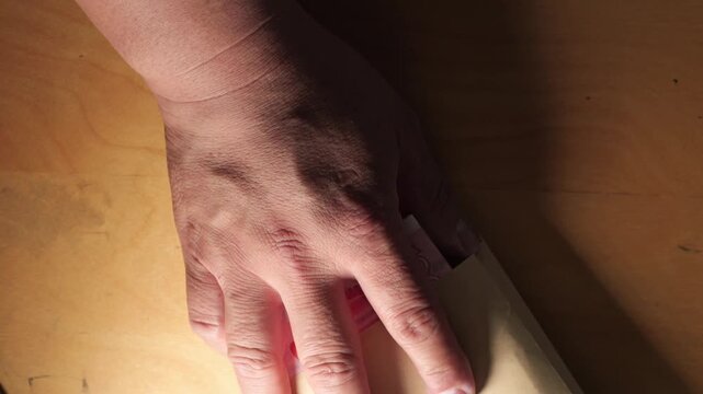 Hands putting Chinese Yuan banknotes inside a brown paper envelope during a cash transaction.