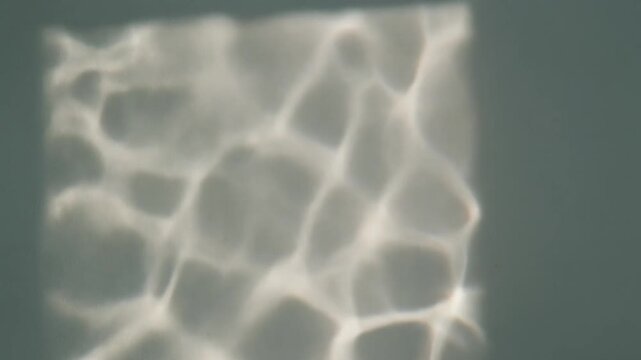 Water light reflections dancing gently on a plain wall