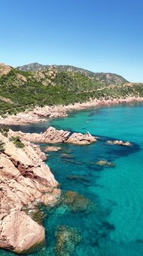 4K drone flight along the Marina di Gairo coastline, featuring Su Sirboni Beach and Cala Laus. Turquoise waters, striking red rocks, and the unspoiled beauty of Sardinia, Italy