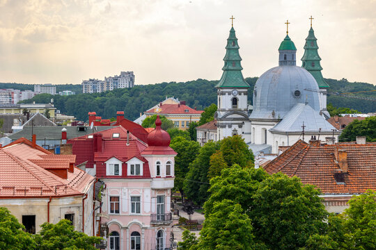 Ternopil, Ukraine, cityscape with a prominent cathedral and its multiple domes and spires. Urban architecture, residential buildings with red roofs, and green trees under a cloudy sky