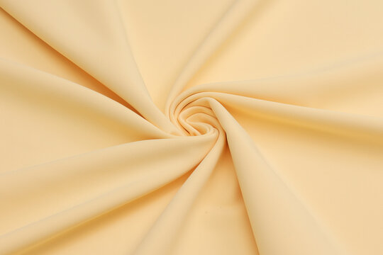 Pastel ye matte crepe fabric texture with a fine, sand-like pebbled grain. High-quality fashion textile material backdrop with an elegant non-reflective surface finish for tailoring and design.