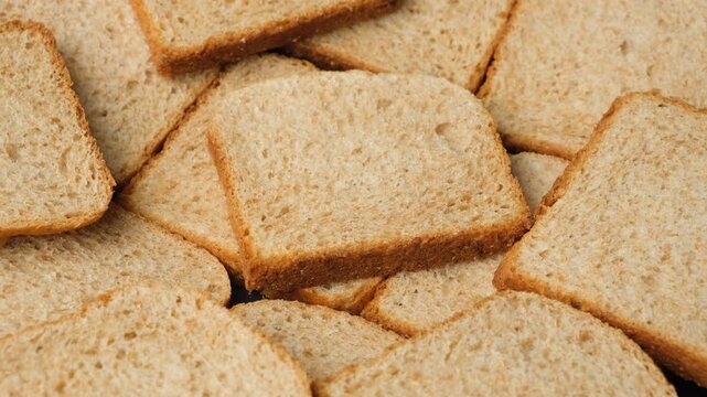 Close-up of a stack of crispy whole wheat toast bread slices rotating slowly.