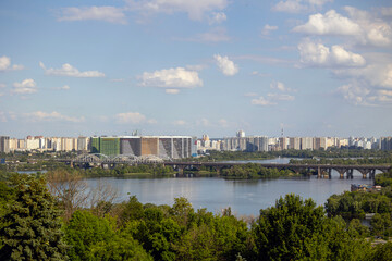 Fototapeta premium Kyiv, Ukraine, a panoramic view of the Dnipro River, with Darnytskyi Bridge connecting to the Left Bank residential areas like Osokorky and Pozniaky in Darnytskyi District, under a cloudy sky