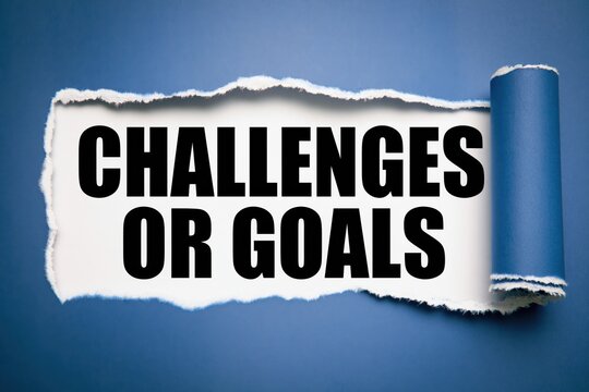 Challenges or goals concept words under ripped dark blue paper